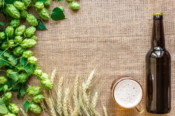 Cerveza de botella y vidrio con ingredientes de elaboración de cerveza. Hop flor con trigo. Vista superior . — Foto de Stock