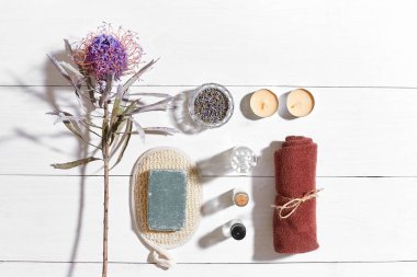 Beyaz ahşap zemin üzerinde kuru çiçek spa set deniz tuzu, uçucu yağ, sabun ve havlu ile süslenmiş