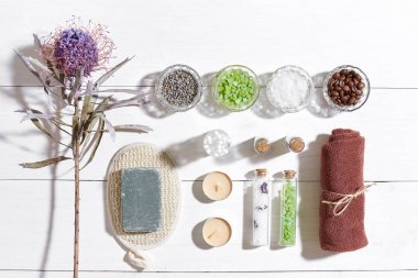 Beyaz ahşap zemin üzerinde kuru çiçek spa set deniz tuzu, uçucu yağ, sabun ve havlu ile süslenmiş