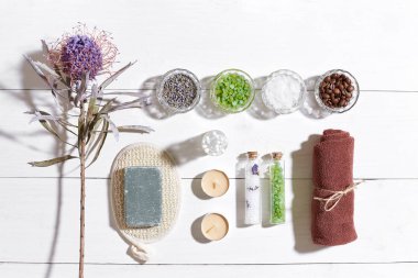 Beyaz ahşap zemin üzerinde kuru çiçek spa set deniz tuzu, uçucu yağ, sabun ve havlu ile süslenmiş