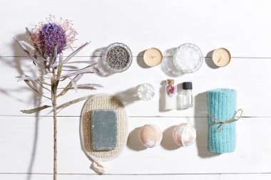 Beyaz ahşap zemin üzerinde kuru çiçek spa set deniz tuzu, uçucu yağ, sabun ve havlu ile süslenmiş