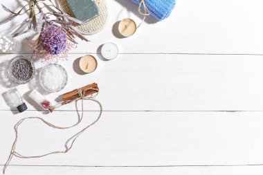 Beyaz ahşap zemin üzerinde kuru çiçek spa set deniz tuzu, uçucu yağ, sabun ve havlu ile süslenmiş