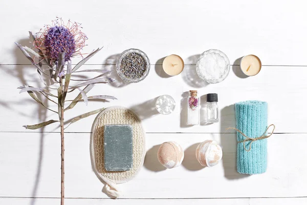 Beyaz ahşap zemin üzerinde kuru çiçek spa set deniz tuzu, uçucu yağ, sabun ve havlu ile süslenmiş
