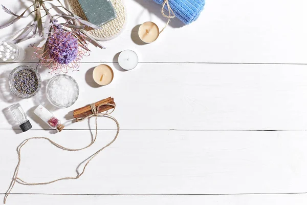 Beyaz ahşap zemin üzerinde kuru çiçek spa set deniz tuzu, uçucu yağ, sabun ve havlu ile süslenmiş