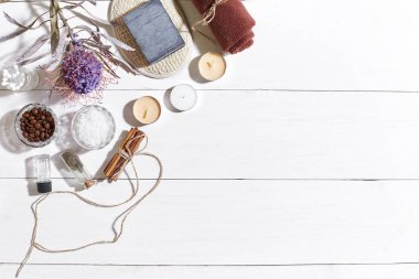 Beyaz ahşap zemin üzerinde kuru çiçek spa set deniz tuzu, uçucu yağ, sabun ve havlu ile süslenmiş