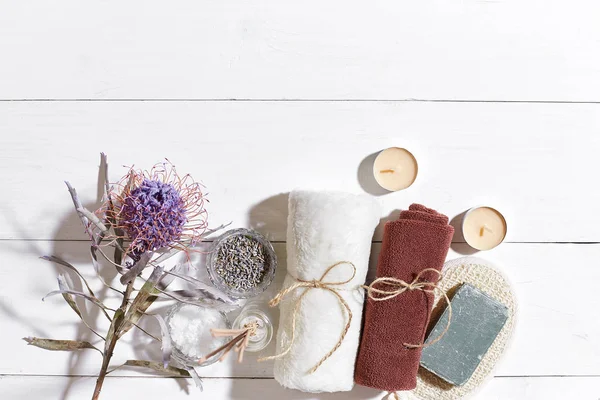 Beyaz ahşap zemin üzerinde kuru çiçek süslenmiş havlu ve sabun ile ayarla spa