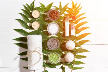 Spa natürmort havlu, mumlar, ile farklı malzemeler için vücut fırçalayın ve yeşil bir beyaz ahşap yüzeye bırakır. Güneş patlaması