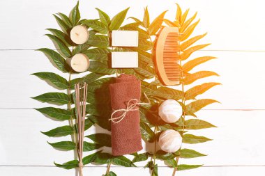 Spa set ile havlu ve sabun yeşil yaprakları ile beyaz ahşap zemin üzerinde. Güneş parlaması