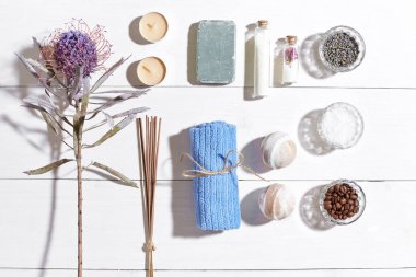 Beyaz ahşap zemin üzerinde kuru çiçek spa set deniz tuzu, uçucu yağ, sabun ve havlu ile süslenmiş