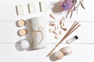 Beyaz ahşap zemin üzerinde kuru çiçek spa set deniz tuzu, uçucu yağ, sabun ve havlu ile süslenmiş