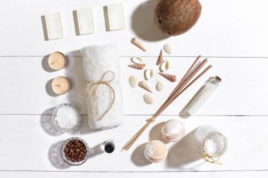 Beyaz ahşap zemin üzerinde deniz kabuklarını spa set deniz tuzu, uçucu yağ, sabun ve havlu ile süslenmiş