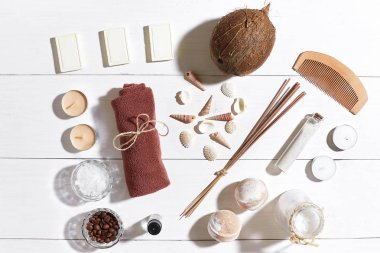 Beyaz ahşap zemin üzerinde deniz kabuklarını spa set deniz tuzu, uçucu yağ, sabun ve havlu ile süslenmiş