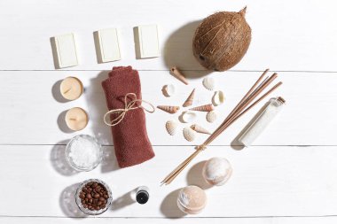 Beyaz ahşap zemin üzerinde deniz kabuklarını spa set deniz tuzu, uçucu yağ, sabun ve havlu ile süslenmiş