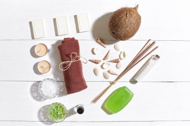 Beyaz ahşap zemin üzerinde deniz kabuklarını spa set deniz tuzu, uçucu yağ, sabun ve havlu ile süslenmiş