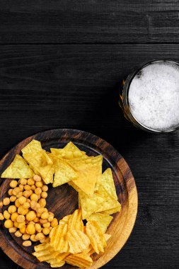 Lager bira ve siyah ahşap masa snacks. Kuruyemiş, cips. Üstten Görünüm ile boşaltmak