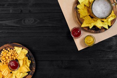 Lager bira ve siyah ahşap masa snacks. Kuruyemiş, cips. Üstten Görünüm ile boşaltmak