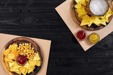 Lager bira ve siyah ahşap masa snacks. Kuruyemiş, cips. Üstten Görünüm ile boşaltmak