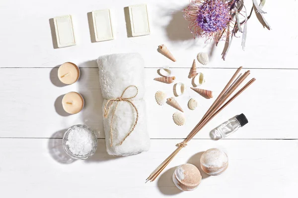Beyaz ahşap zemin üzerinde kuru çiçek spa set deniz tuzu, uçucu yağ, sabun ve havlu ile süslenmiş