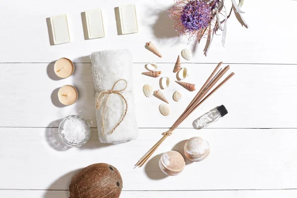 Beyaz ahşap zemin üzerinde kuru çiçek spa set deniz tuzu, uçucu yağ, sabun ve havlu ile süslenmiş