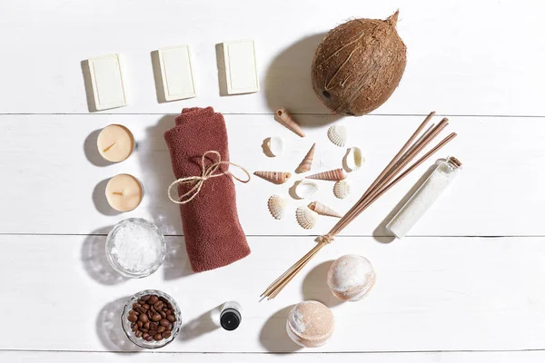 Beyaz ahşap zemin üzerinde deniz kabuklarını spa set deniz tuzu, uçucu yağ, sabun ve havlu ile süslenmiş