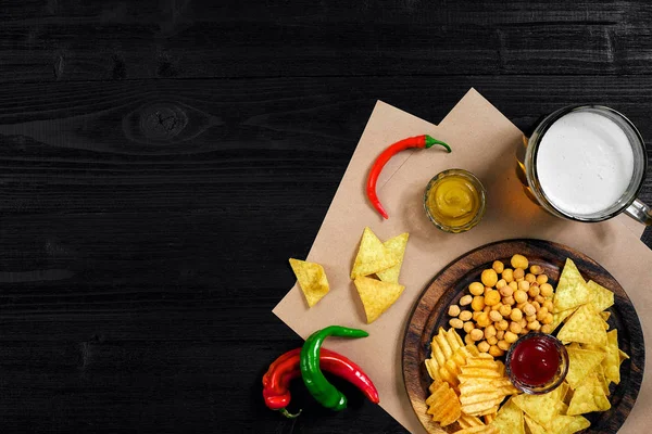 Lager bira ve siyah ahşap masa snacks. Kuruyemiş, cips. Üstten Görünüm ile boşaltmak