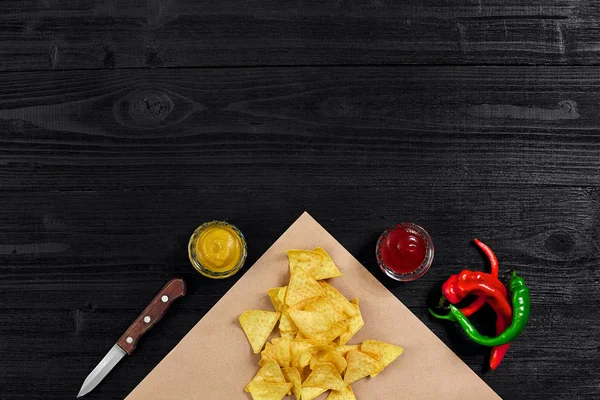 Tortilla cips sosu ve kırmızı biber ile üstten görünüm siyah ahşap zemin üzerine