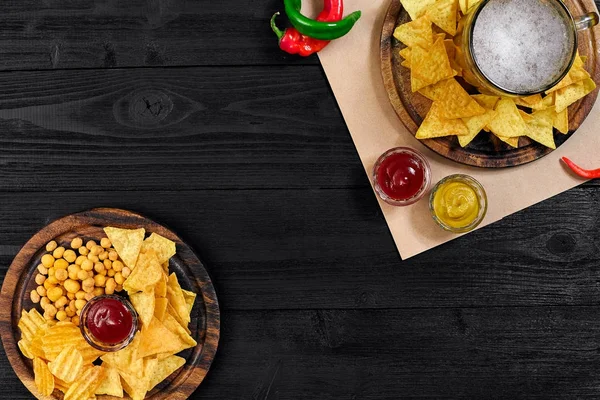 Lager bira ve siyah ahşap masa snacks. Kuruyemiş, cips. Üstten Görünüm ile boşaltmak