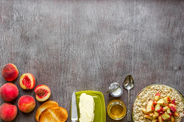 Harina de avena con melocotón, tostadas con mantequilla y miel sobre una mesa de madera. El concepto de un desayuno saludable — Foto de Stock