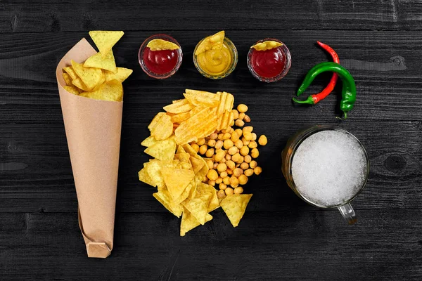 Siyah ahşap masa üzerinde bira cam ve aperatifler soslu havai görünümü.