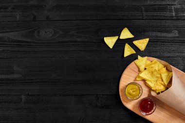 Siyah ahşap masa üzerinde hardal ve domates soslu tortilla cips. Üstten Görünüm