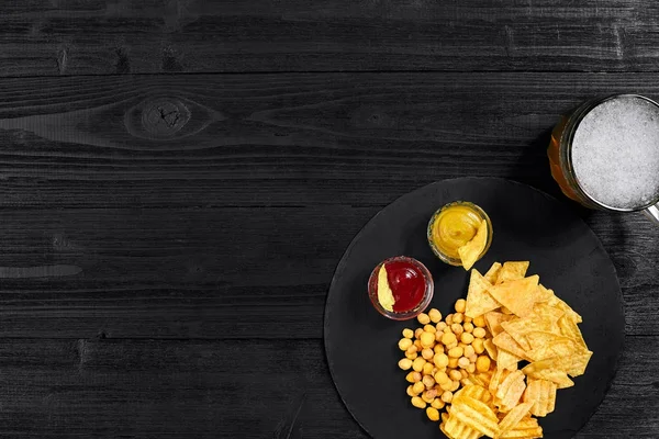 Siyah ahşap masa üzerinde bira cam ve aperatifler soslu havai görünümü.