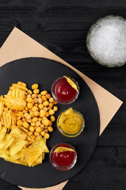 Siyah ahşap masa üzerinde bira cam ve aperatifler soslu havai görünümü.