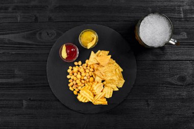 Siyah ahşap masa üzerinde bira cam ve aperatifler soslu havai görünümü.