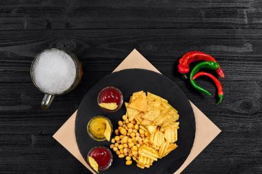 Siyah ahşap masa üzerinde bira cam ve aperatifler soslu havai görünümü.