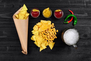 Siyah ahşap masa üzerinde bira cam ve aperatifler soslu havai görünümü.