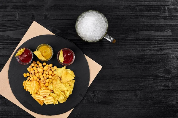 Siyah ahşap masa üzerinde bira cam ve aperatifler soslu havai görünümü.