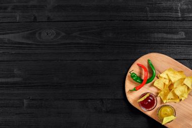 Siyah ahşap masa üzerinde hardal ve domates soslu tortilla cips. Üstten Görünüm