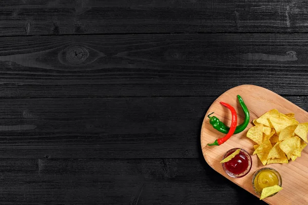Siyah ahşap masa üzerinde hardal ve domates soslu tortilla cips. Üstten Görünüm
