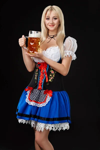 Giovane donna sexy indossa un dirndl con boccale di birra su sfondo nero . — Foto Stock