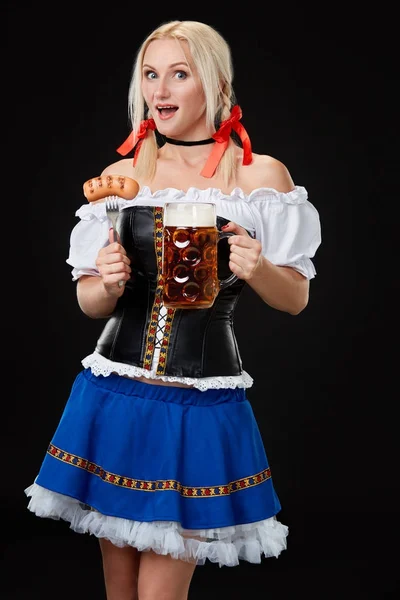 Young sexy woman wearing a dirndl with beer mug on black background. — Stock Photo, Image