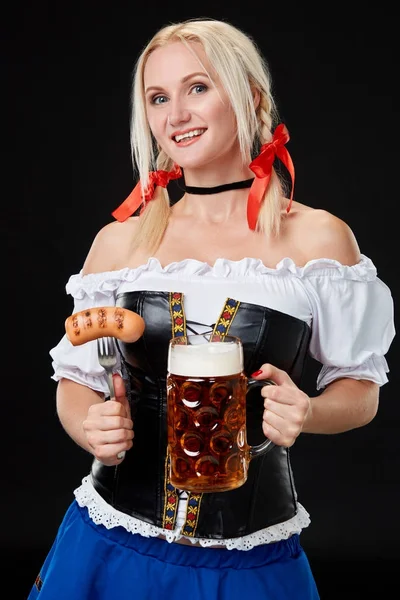 Junge sexy Frau trägt ein Dirndl mit Bierkrug auf schwarzem Hintergrund. — Stockfoto