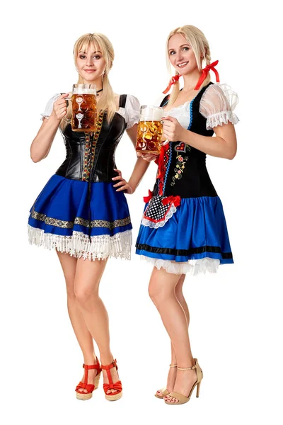 Pełna długość Portret dwóch womans blond z tradycyjnych strojach gospodarstwa szklanki piwa na białym tle. — Zdjęcie stockowe