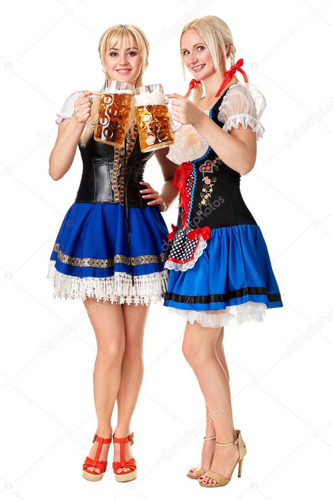 Full length portrait of a two blond womans with traditional costume holding beer glasses isolated on white background.