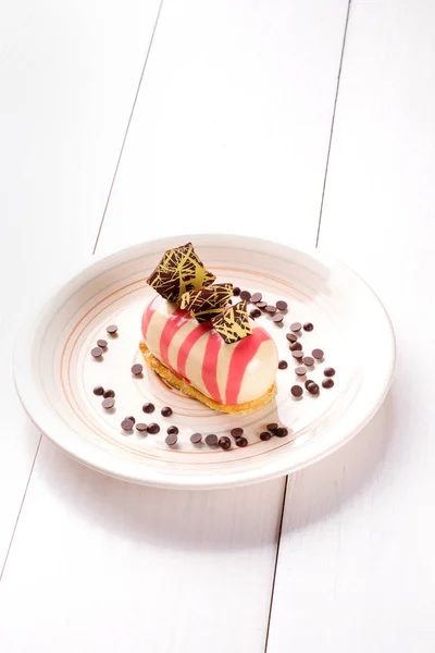 Kleiner Kuchen mit verschiedenen Füllungen auf einem weißen Teller. weißer Holztisch. — Stockfoto