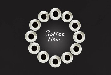 Bardak kahve ile bir daire içinde yığılmış. Saat yirmi bardak oluşur. Siyah arka plan. Kavram zaman kahve için