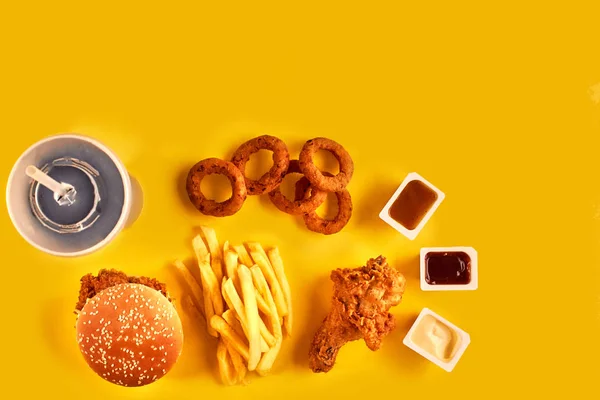 Piatto fast food vista dall'alto. Patatine fritte, hamburger, maionese e salse al ketchup su fondo giallo . — Foto Stock