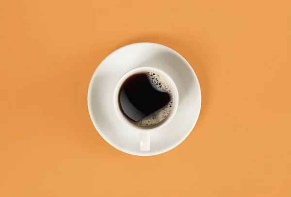 Flechas de un reloj en una taza de café sobre fondo naranja. Vista desde arriba . — Foto de Stock