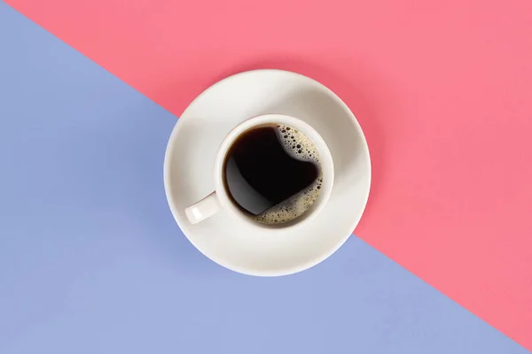 Una taza de café negro sobre fondo rosa y lila. Vista desde arriba . — Foto de Stock