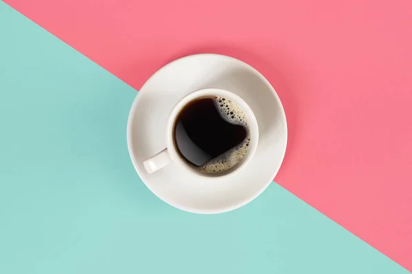 Una taza de café negro sobre fondo azul y rosa. Vista desde arriba . — Foto de Stock