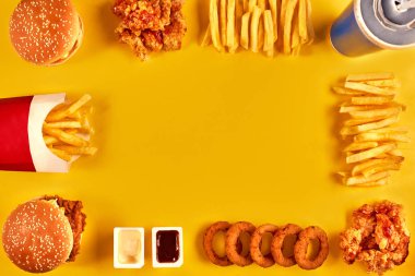 Üstten Görünüm hamburger, patates kızartması ve Sarı zemin üzerine kızarmış tavuk. Metniniz için kopya alanı.